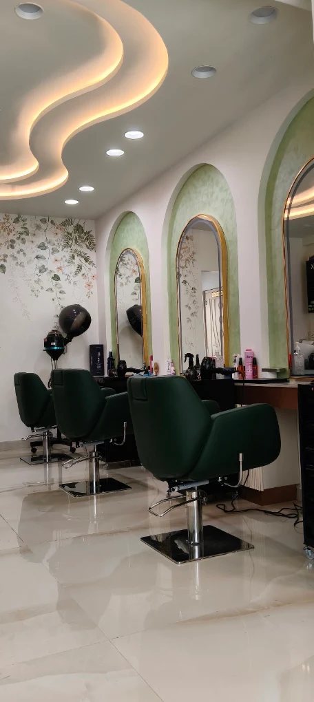 Inside Avis Salon: green styling chairs, arched gold-framed mirrors and a sculpted ceiling light