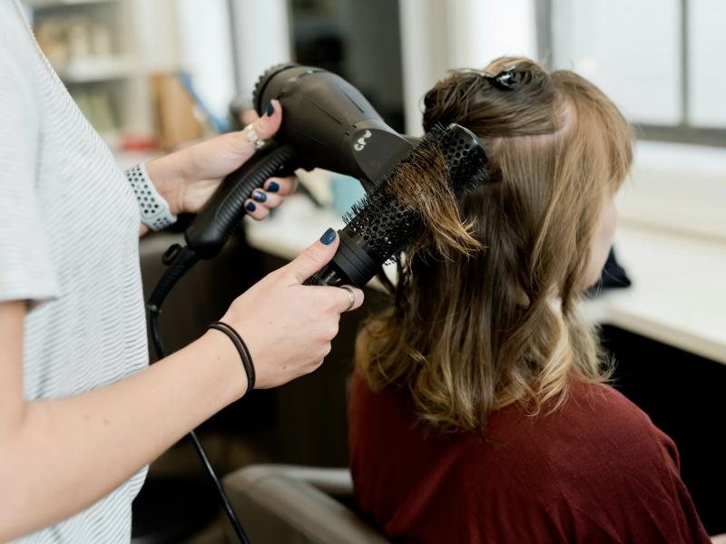 A stylist working with a round brush and dryer